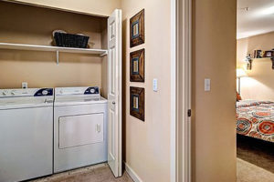 Washer and dryer closet in hallway next to bedroom, white doors