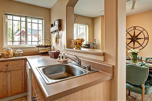 Kitchen sink, natural light, brown countertops, window looking into dining area