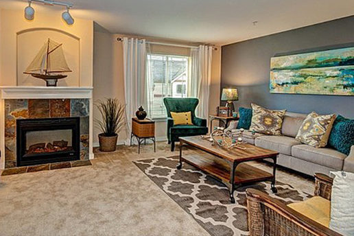 Decorated carpet living room with gray wall, fireplace, couch and chairs