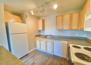 Unit Kitchen, Light brown cabinetry, White Appliances, Wood Floors, Breakfast bar.