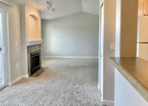 Unit Living Room, Carpeted floor, Fireplace, high ceilings, neutral toned walls, unfurnished