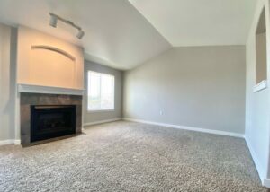 Unit Living room, Large Window right of fireplace, Patio door left of fireplace, Carpet flooring, high ceiling.