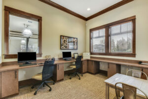 Business Center, multiple work stations with community computers, small 2 person desks, neutral contemporary carpeting, with Rustic Decor.