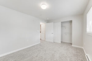 Interior Unit Bedroom, white walls, neutral toned carpeting, sliding closet door.