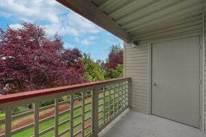 Exterior Unit Patio, wood railing, storage closet on patio, view of trees in bloom and surrounding landscaping.
