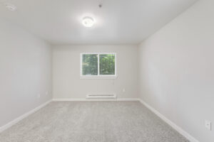 Interior Unit bedroom, central ac, white walls, neutral toned carpeting, ceiling light fixture.