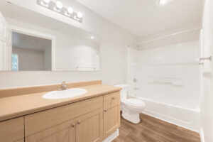 Interior Unit Bathroom, laminate countertop. lightbrown cabinets, white appliances, shower/bathtub, large mirrored vanity.
