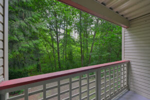 Exterior Unit patio, view of dense woods, wood railing, outdoor storage closet attached to patio