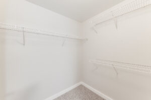 Interior Unit Walk-in Closet, 3 shelves for clothes storage, white walls, neutral toned carpeting.